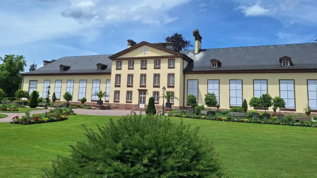 Żółty budynek z gniazdami bocianów na dachu w parku de l'Orangerie