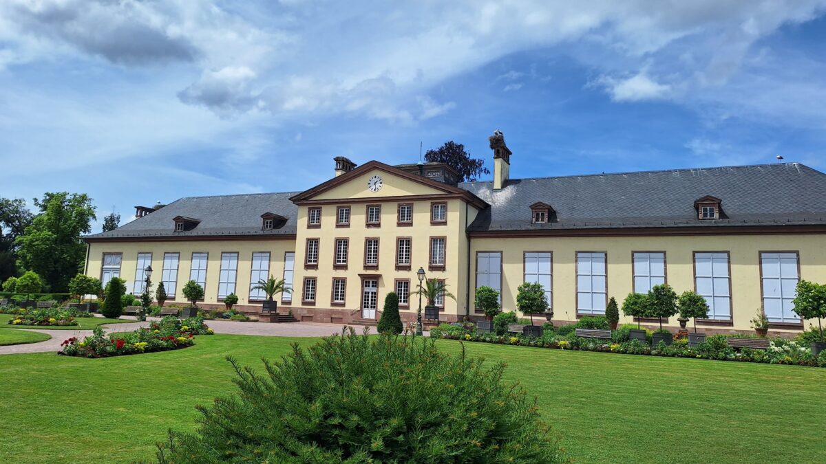 Żółty budynek z gniazdami bocianów na dachu w parku de l'Orangerie